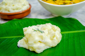 Closeup of tapioca cooked in coconut milk on a banana leaf with fish curry and more tapioca (Pal Kappa)