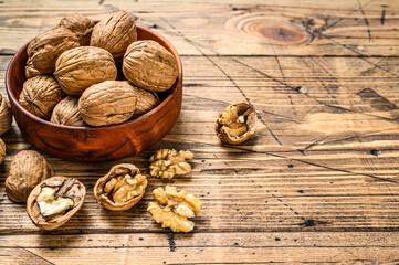 Walnuts in a wooden plate and walnut kernels. Gray background. Top view. Copy space