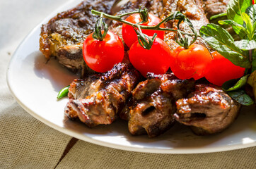 Fresh, homemade grilled beef skewers with vegetables and spices, with barbecue sauce and ketchup, on a white plate close-up