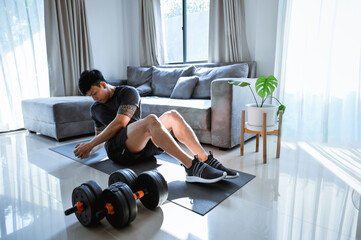Fototapeta premium Exercises at Home. Active Asia man doing Crunch twist in living room.
