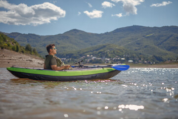 Young man in a canoe fishing on a lake