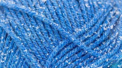 Abstract background - threads of blue knitted yarn with small grains of snow and water droplets