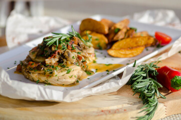 Country style fried potatoes with chicken breast in mushroom sauce on a rectangular white plate