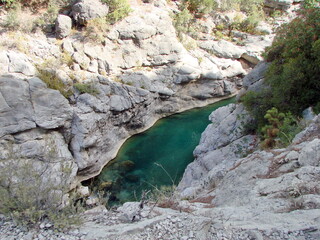 The natural picture from above of the azure calm surface of the mountain river which sharply contrasts with gray rocky coasts under rays of the sun.