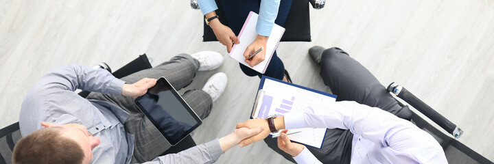 Three people sit on chair in circle top view. Woman in shirt write with pen in blank pad. Two men...