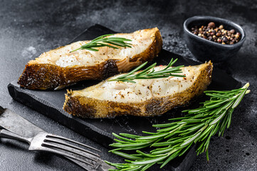 Halibut fish steak with rosemary. Black background. Top view
