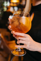 Bright orange cocktail being displayed infront of bar interier