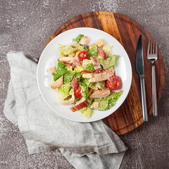 Healthy organic chicken caesar salad. Fresh caesar salad with grilled chicken in wooden plate. Grilled chicken breast with bacon and fresh vegetables.