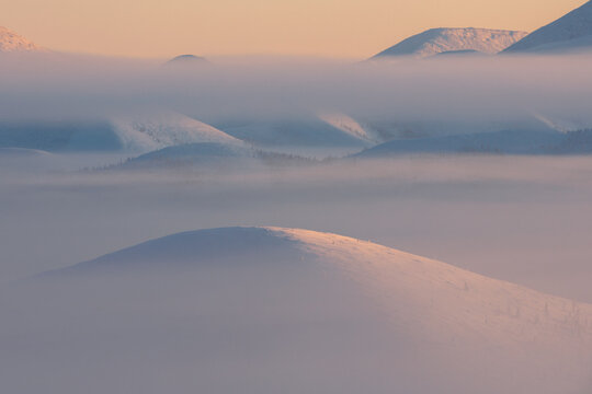 Fog on the Olchansky pass in the Oymyakonsky district. Morning landscape of snow-capped mountains. Foggy landscape of the coldest place on Earth - Oymyakon