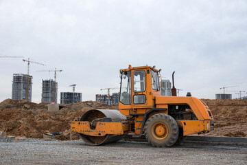 Vibro Roller Soil Compactor leveling soil at construction site. Excavator and vibration single-cylinder road roller during the construction of road. Road work project. Laying new asphalt