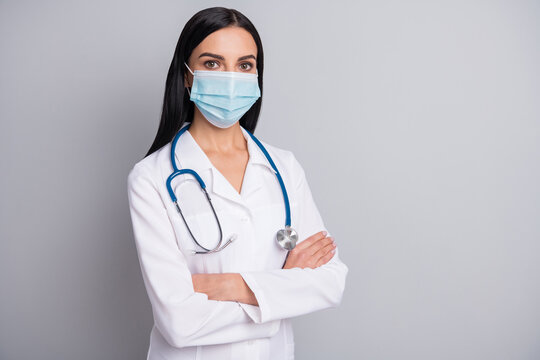 Photo of confident serious lady doctor wear white coat face mask arms crossed empty space isolated grey color background