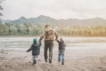 Father and sons running on the beach of river