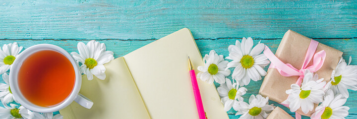 Cozy breakfast in spring or early autumn tea with bouquet of daisy flowers and note book. Copy space, top view flat lay