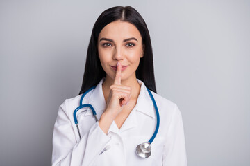Photo of flirty doctor girl finger cover lips wear stethoscope white uniform isolated grey color...