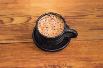 Coffee in a black ceramic cup on a rustic table