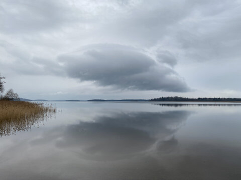 Soft cloud formation of one cloud over water. Beautiful tranquil gray winter scene.