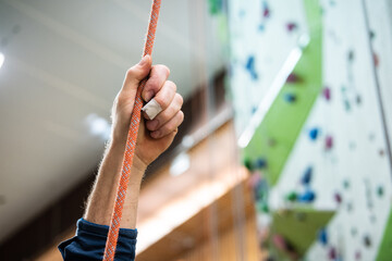 Eine Person hält ein Seil zur Sicherung in einer Kletterhalle