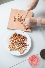 Girl's hands chop hazelnuts for filling in homemade chocolate