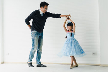 An Asian father and daughter are dancing, dad teaches daughters to dance in a fun room