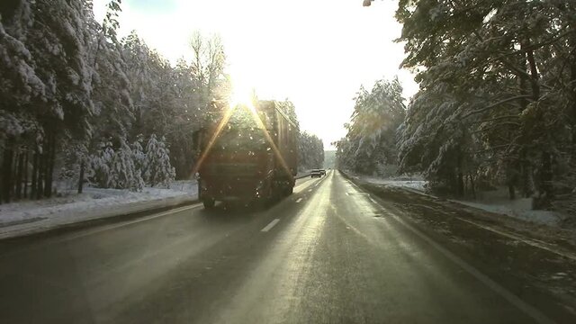 Beautiful winter road with trees in the snow with cars in the sun