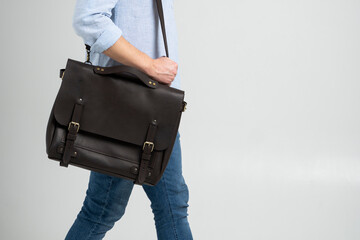 Brown men's shoulder leather bag for a documents and laptop on the shoulders of a man in a blue...