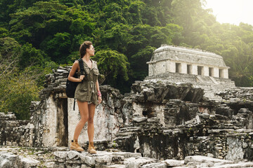 Woman with a backpack beside ancient Mayan ruins