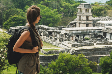 Woman with a backpack beside ancient Mayan ruins