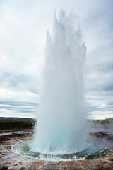 The Great Geysir, geyser in southwestern Iceland, Haukadalur valley, Geyser splashing out of the ground against the background of a cloudy sky, abstract vertical background with water
