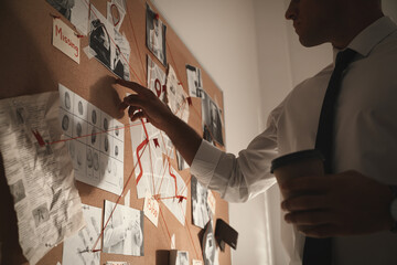 Detective looking at evidence board in office, closeup