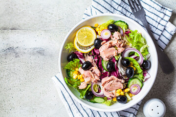 Tuna salad with cucumbers, corn, olives and red onions in white bowl, top view. Comfort food...