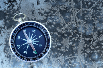 Fototapeta na wymiar Classic navigation compass on winter frozen background as symbol of tourism with compass, travel with compass and outdoor activities with compass