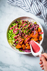 Vegan salad bowl with baked sweet potato, edamame beans, nuts and pink beetroot dressing. Vegan food concept.