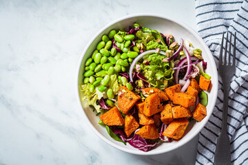 Vegan salad bowl with baked sweet potato, edamame beans, nuts and onion. Vegan food concept.