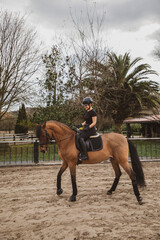 woman riding her brown horse with black mane dressed in black with a helmet