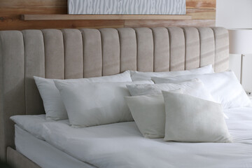 Bed with soft pillows in room. Modern interior