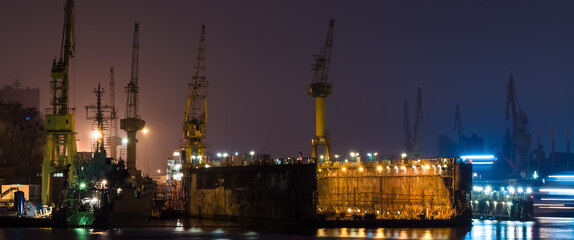 SHIPYARD - A floating repair dock and port cranes on the wharves  