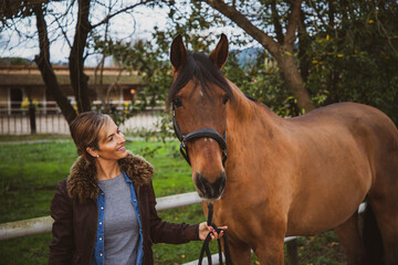 Fototapeta premium Cheerful and smiling woman looking at her horse