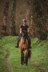 Foto op Canvas woman riding her brown horse with black mane dressed in black with a helmet © Alvaro Postigo 