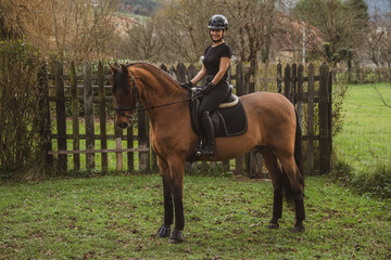 woman riding her brown horse with black mane dressed in black with a helmet