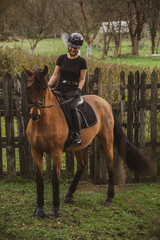 woman riding her brown horse with black mane dressed in black with a helmet