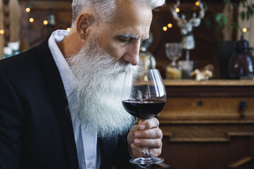 Handsome bearded senior man drinking red wine