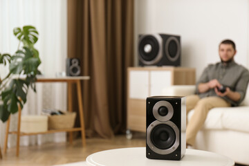 Man using remote to control modern audio speaker system in bright room