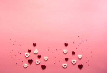 Decorations for design for valentine's day on a pink background. Sparkling white and red paper hearts of different sizes. Flat lay top view. Copy space