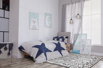 Bed with stylish linens in children's room. Interior design