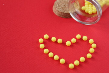Vitamins tablet homeopathy poured out of jars lie heart on red background with a copy of the space place for text.