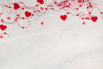 Red hearts and red beads with hearts on white stone background.Valentine's Day background. Valentine's Day concept. Flat lay.