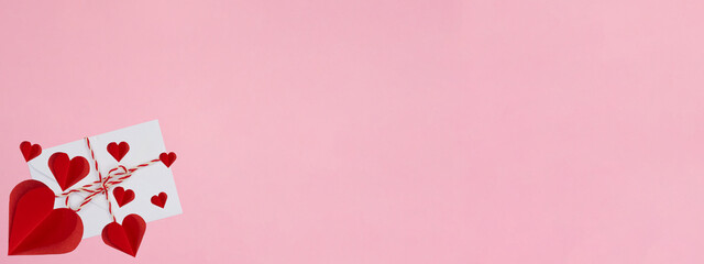 Valentine's day Love Wedding Birthday background banner panorama long greeting card - White envelope with white red ribbon and red hearts isolated on pink paper texture, top view flat lay