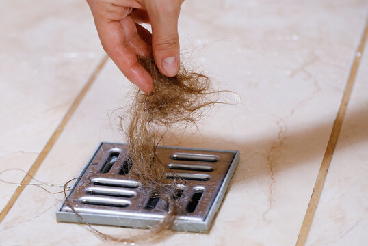 Woman removing hair clump from the shower drain
