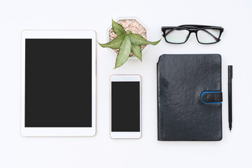 White office desk with notebook, tablet, mobile phone, glasses and pen. Blank mobile phone and notepad for input text. Business, finance concept. Top view, flat lay and copy space