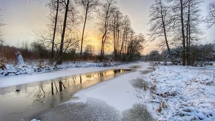 zimowy krajobraz częściowo zamarzniętej rzeki koło Włodawy dużo śniegu niebieskie niebo złota godzina 